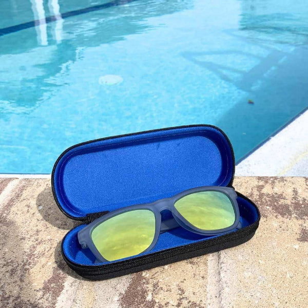 Yellow Sunglasses Polarized in a blue case by a swimming pool, showcasing their vibrant color and outdoor utility.