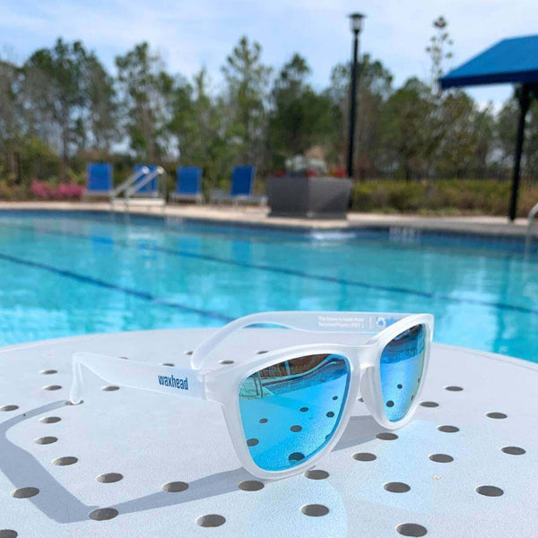 White Sunglasses Polarized resting by the pool with blue lenses, made from recycled plastic for sun and style.