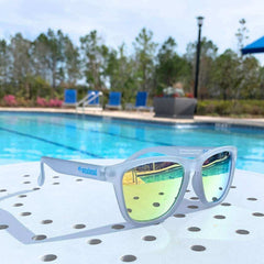 Yellow Sunglasses Polarized on a table by a pool, perfect for outdoor activities and made from recycled plastic.