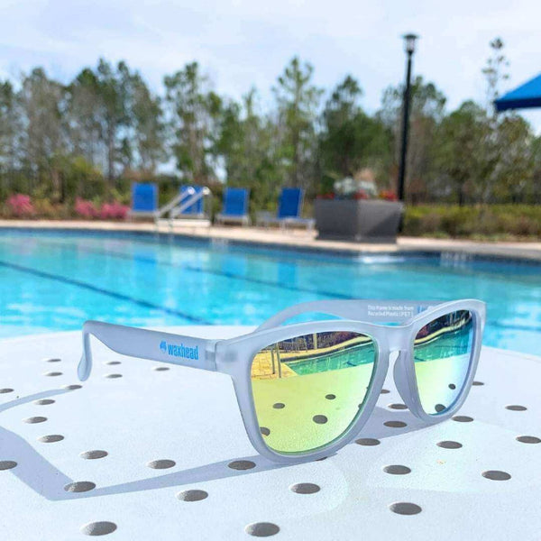 Yellow Sunglasses Polarized on a table by a pool, perfect for outdoor activities and made from recycled plastic.