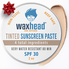 Waxhead sunscreen paste container with a red bow on a white background