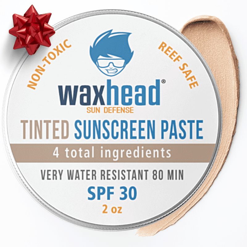 Waxhead sunscreen paste container with a red bow on a white background